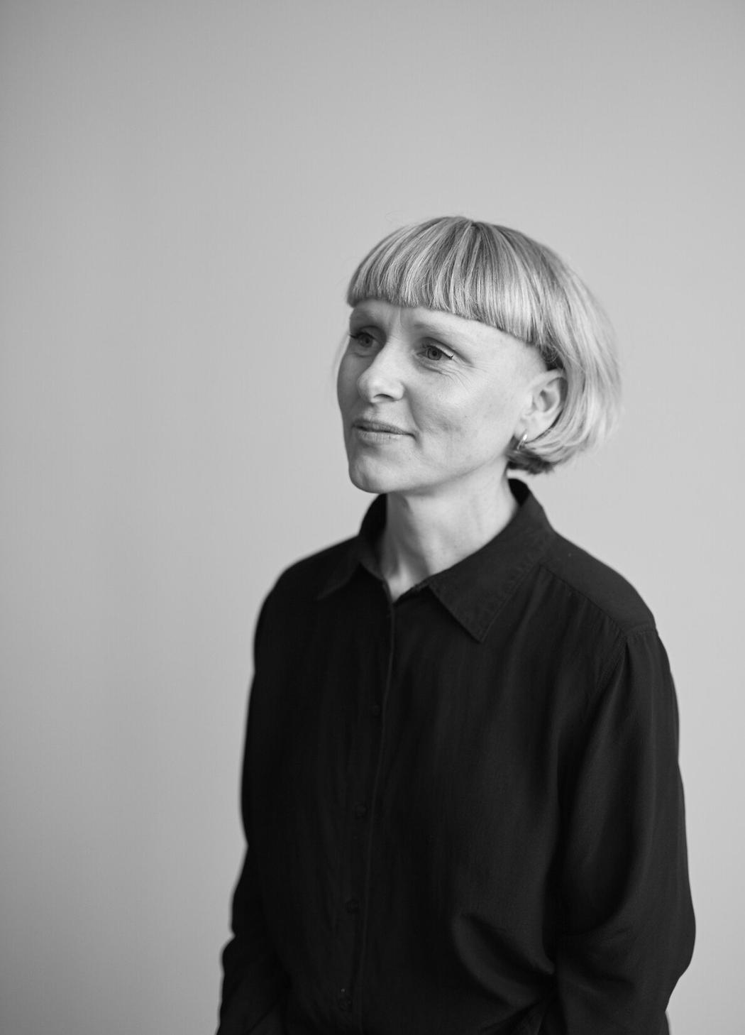 A black and white photo of a person in a black blouse.